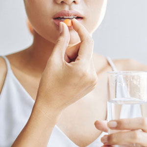 Young woman injesting a capsule