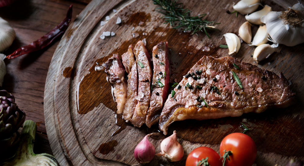  A part-sliced steak on a wooden dish