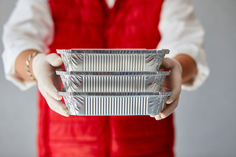 A man in an elegant uniform handing well wrapped ready-to-eat meals