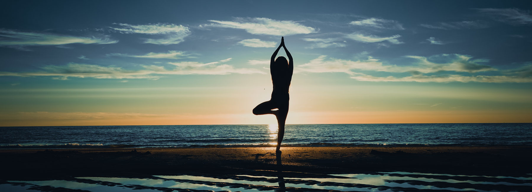 Silouhette of an individual practincing yoga on a  beach